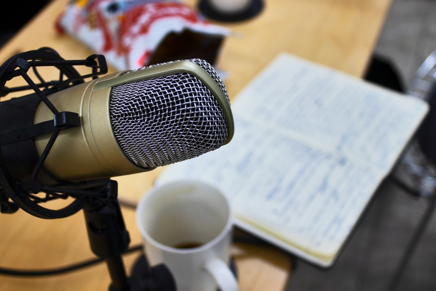 Podcast microphone and a cup of coffee on a desk with notes.